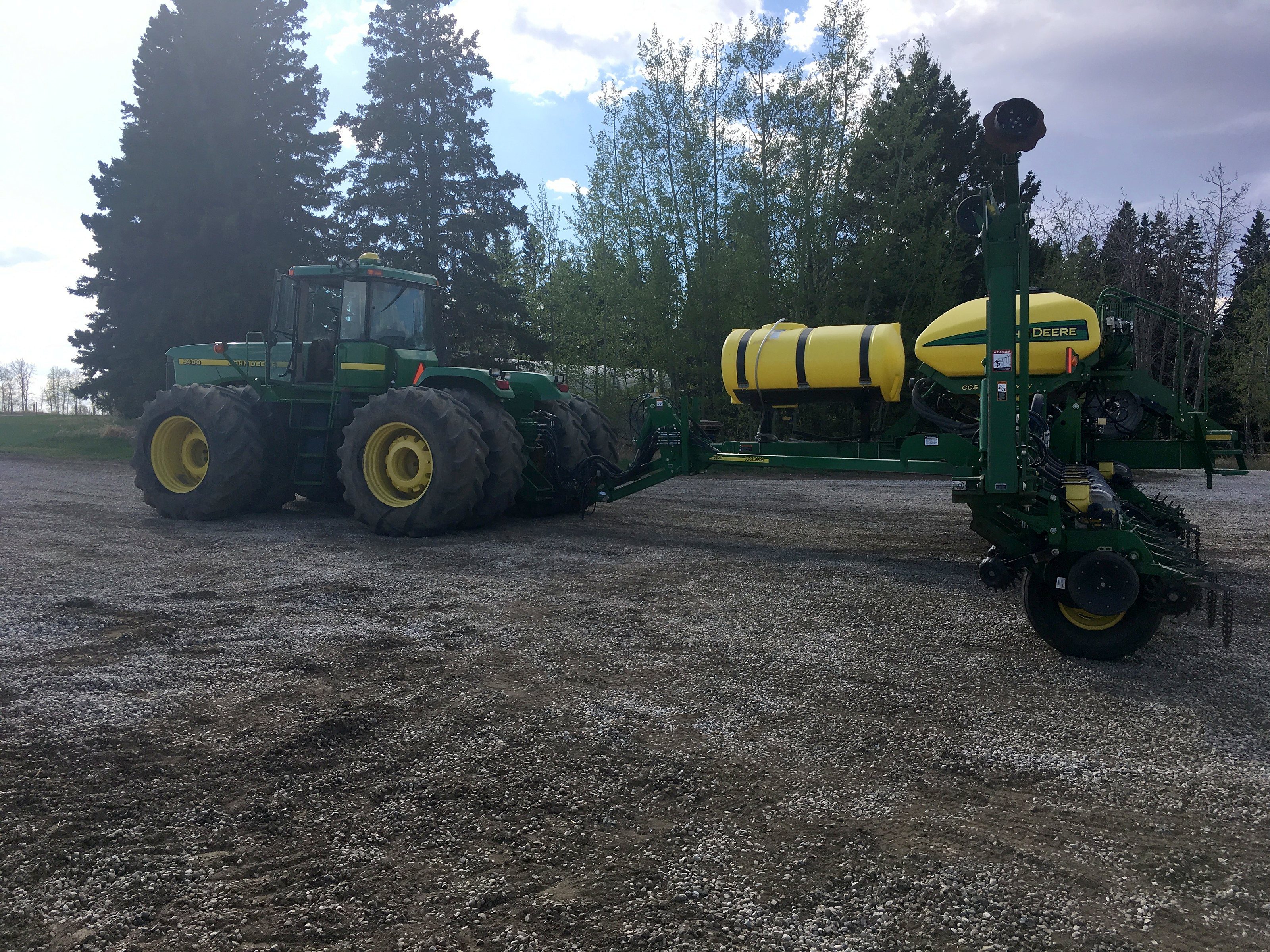 A four-wheel-drive tractor with an air seeder behind it in spring