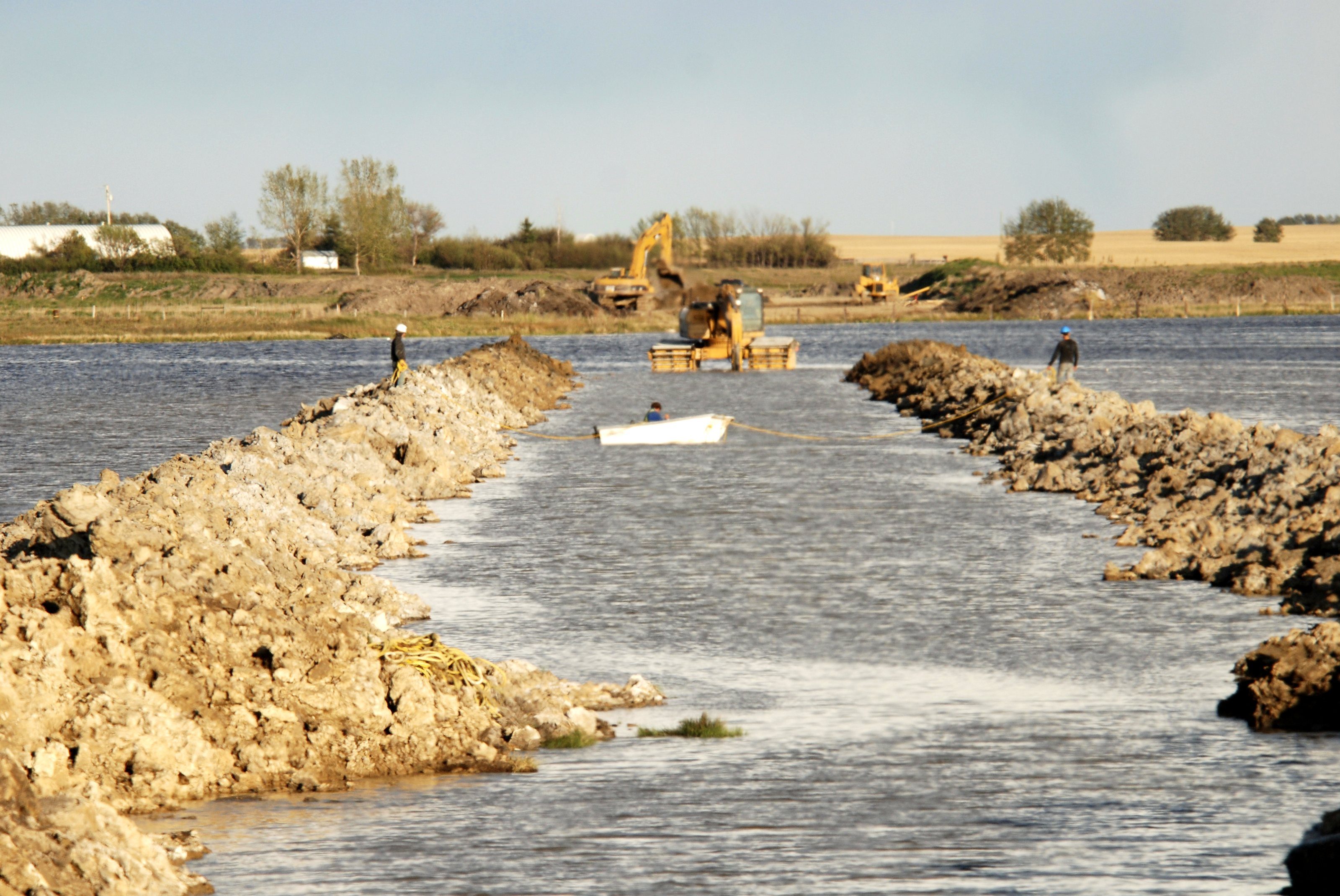 Rock placed across open water with machines working at the far end
