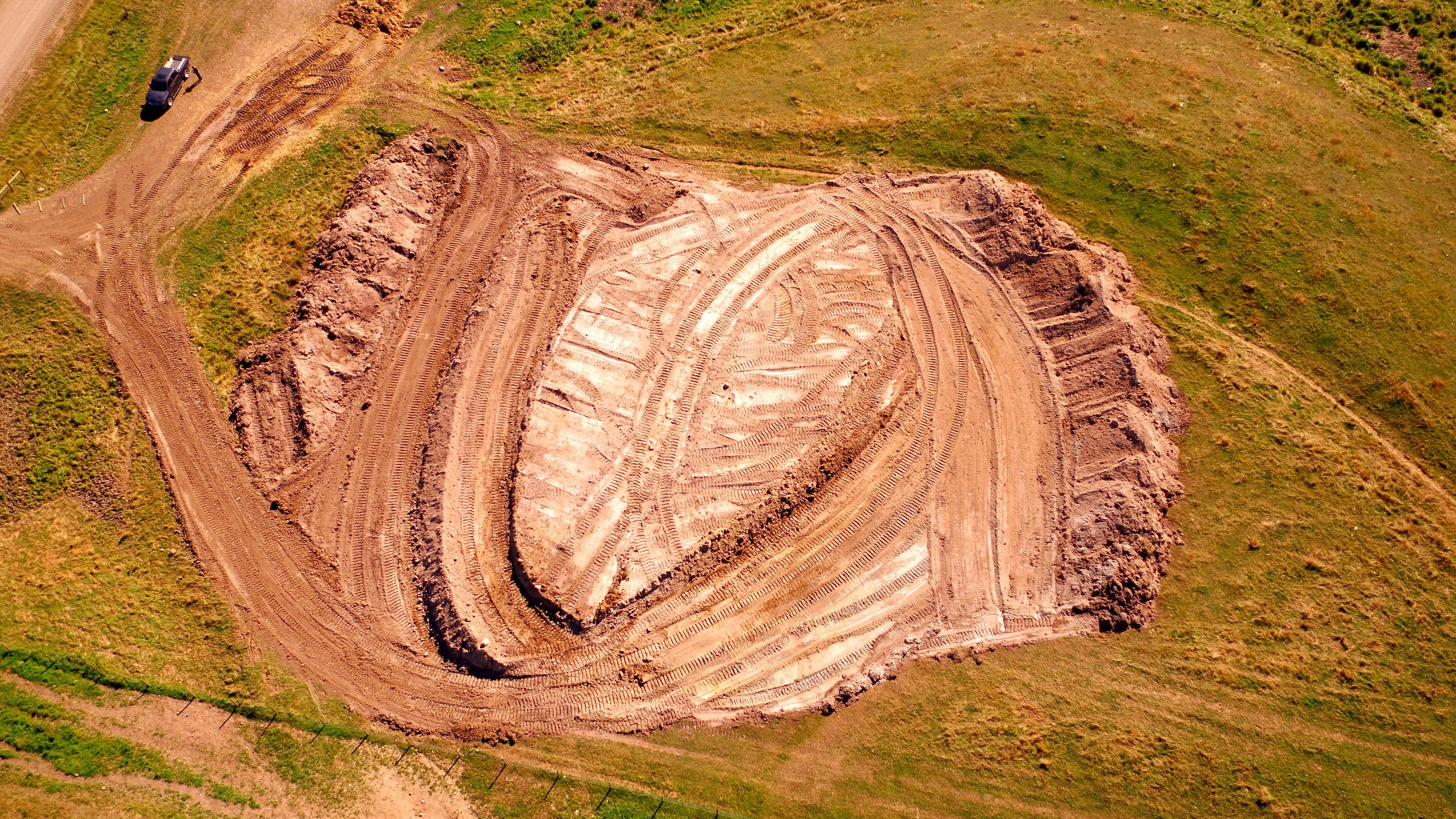 A borrow pit from the air, the cut face, the floor and a scraper at work