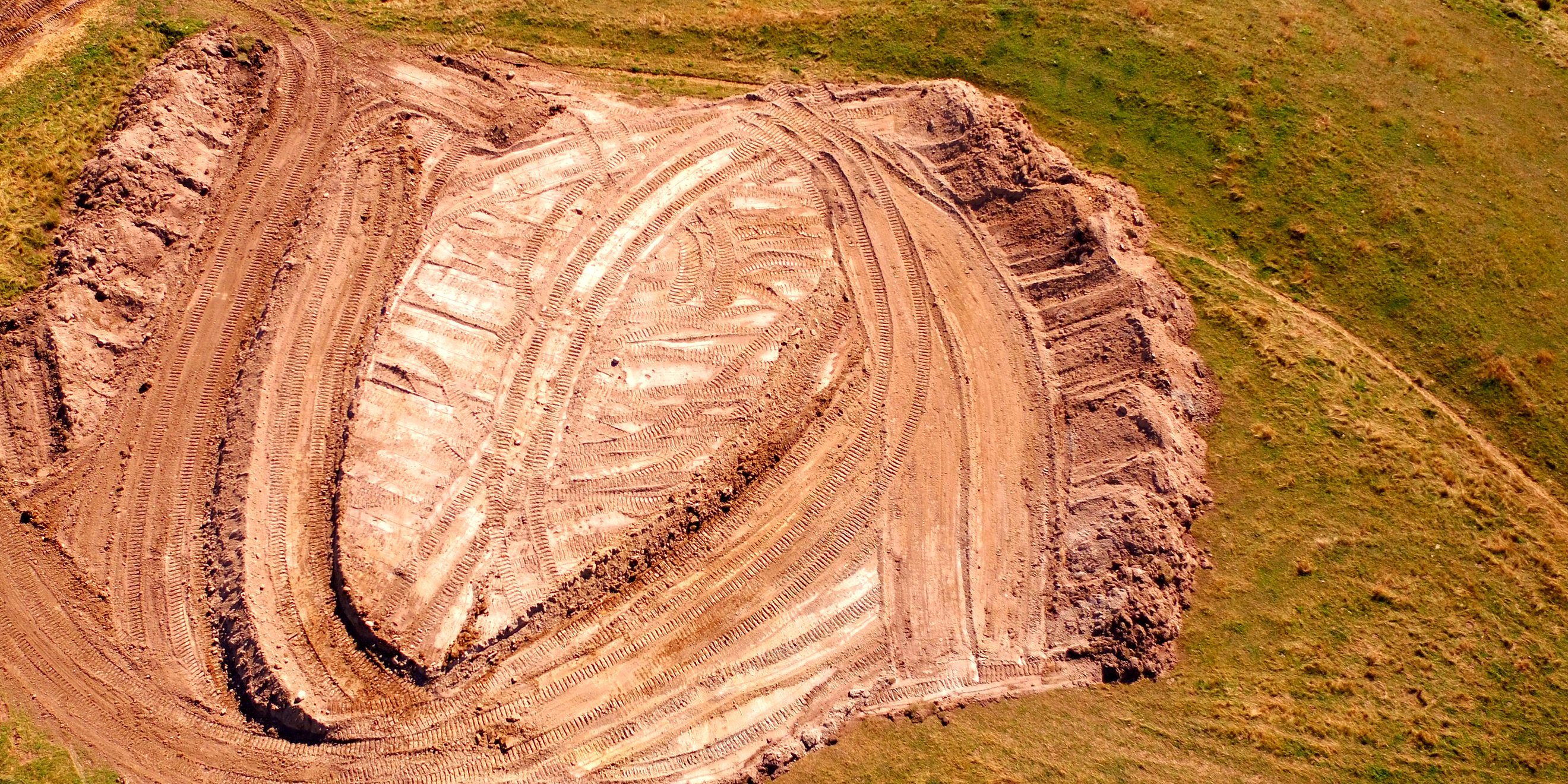 The floor and face of a borrow pit from the air, cut in bands
