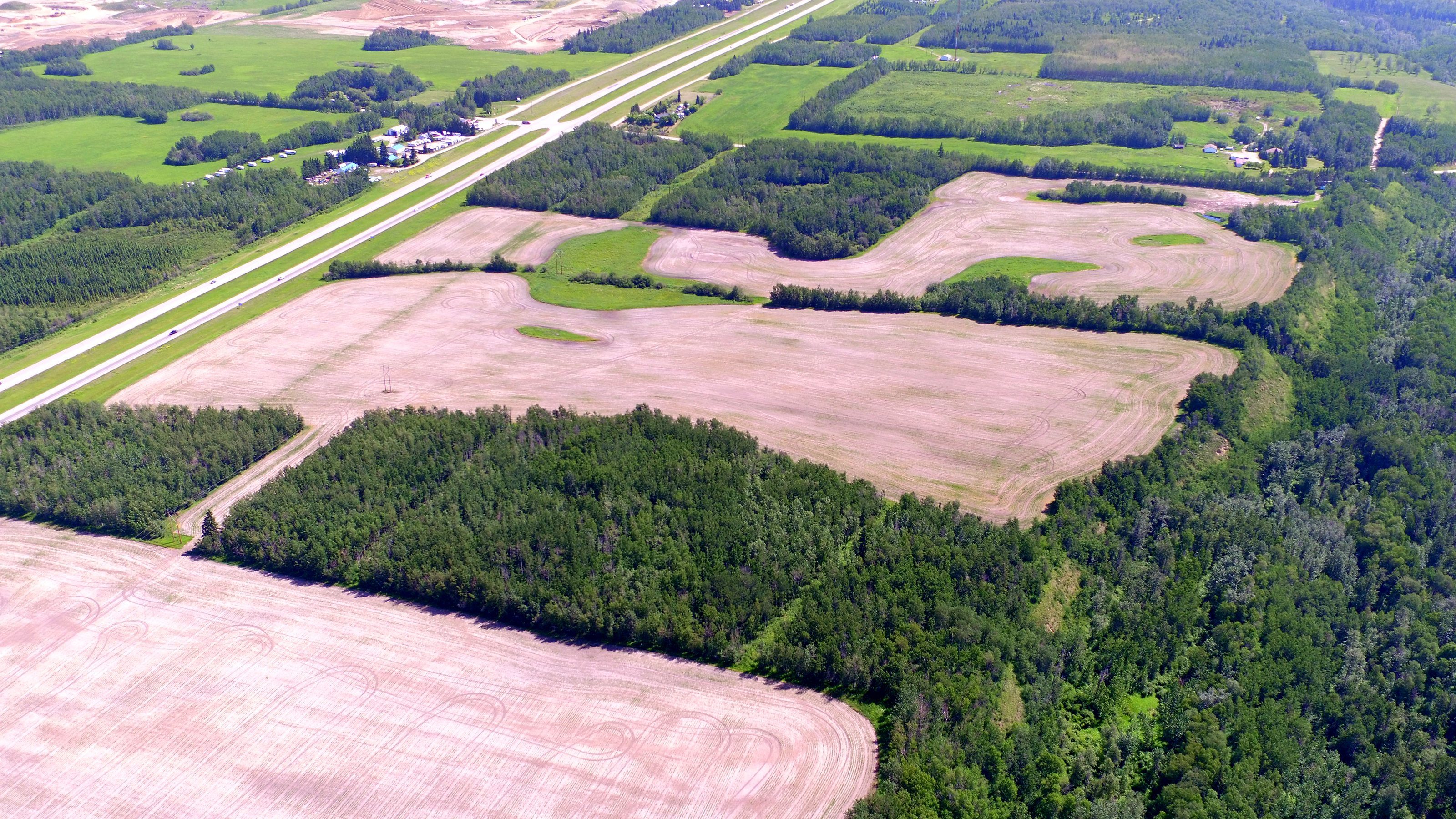 Crop land from the air, a road running between fields with a treeline beyond