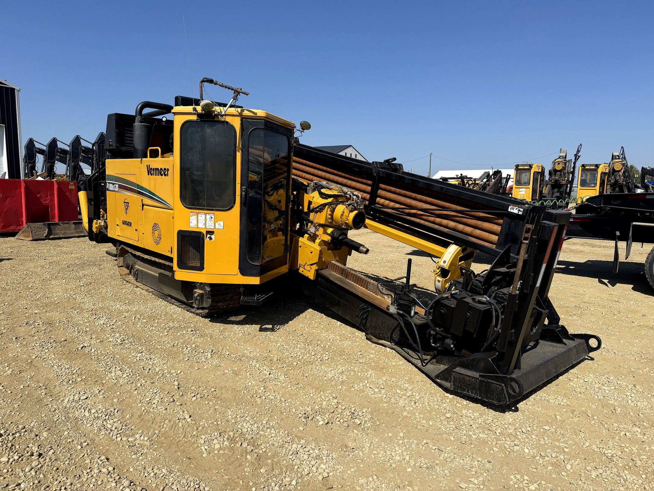 A directional drill on tracks in the yard with the rod string racked along its frame