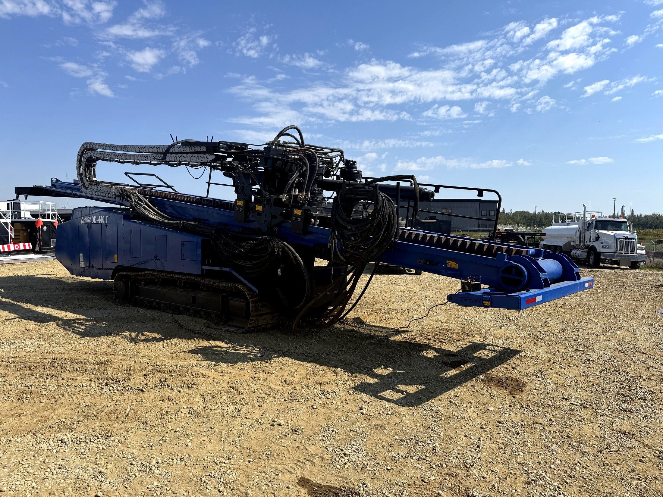 A directional drill rig standing in the yard with its drill stem racked
