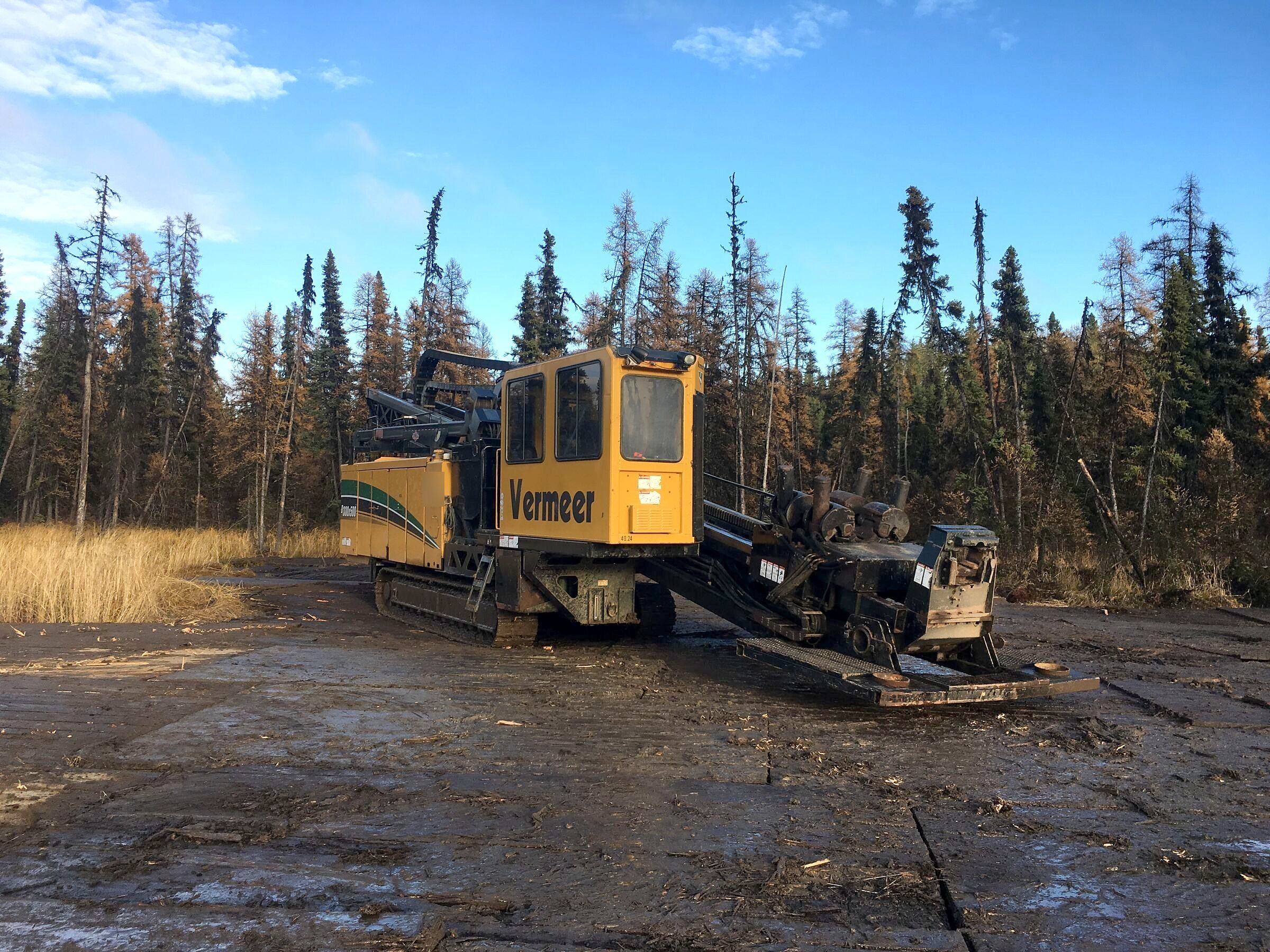 A directional drill rig at the treeline in low winter sun
