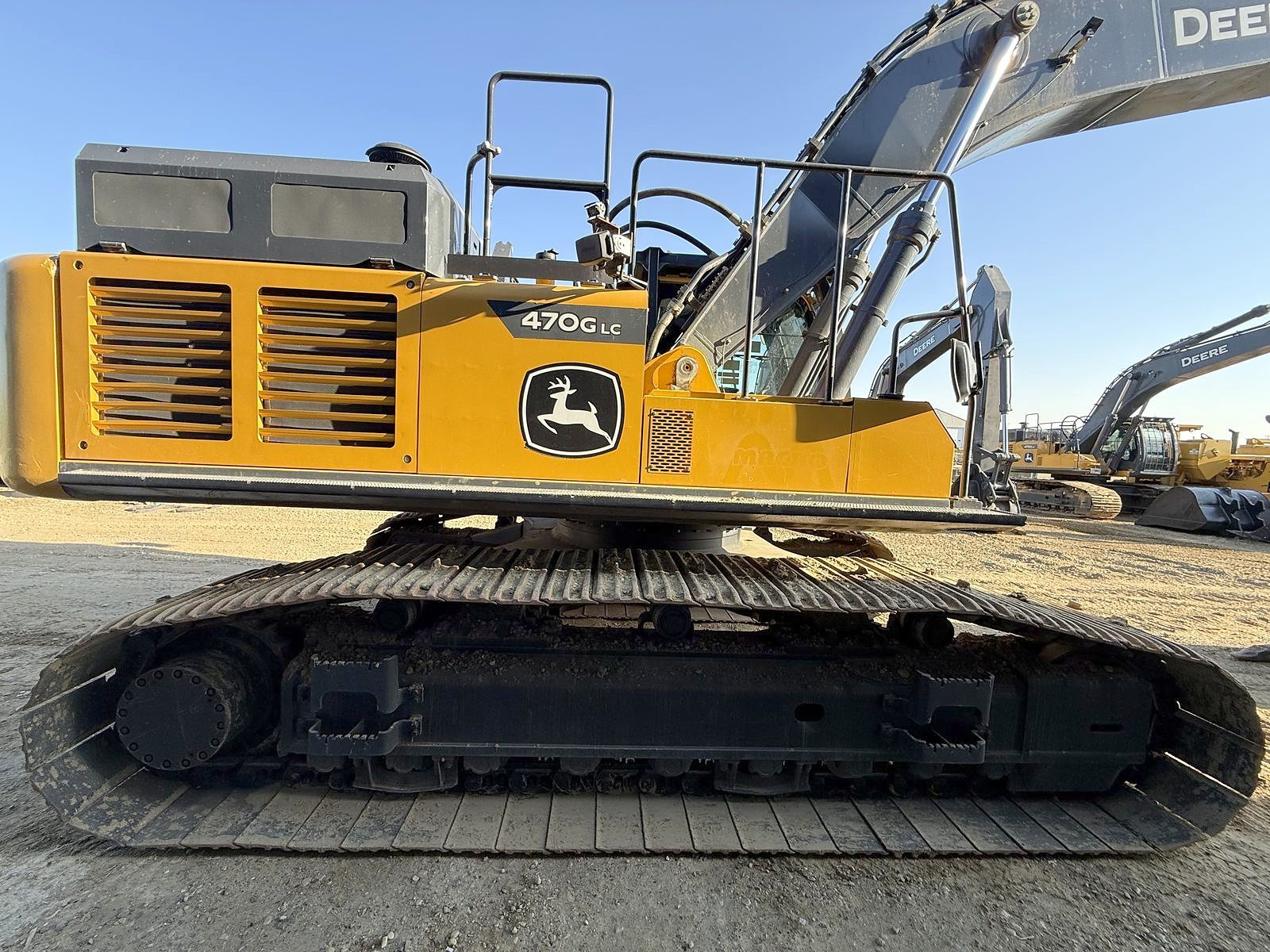A large tracked excavator in the yard, boom raised, side view