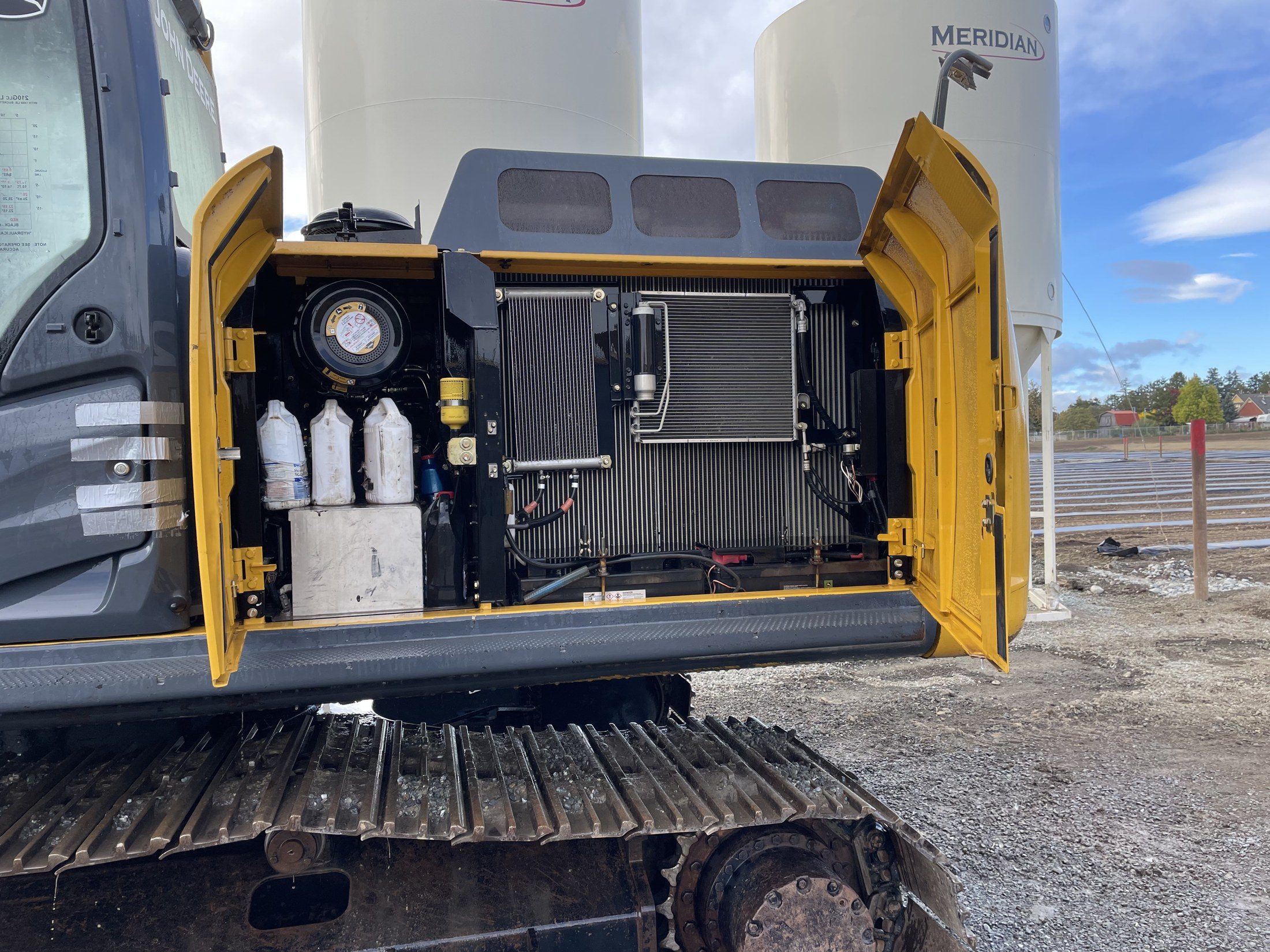 An excavator with its engine bay doors open, the coolers and the service side showing