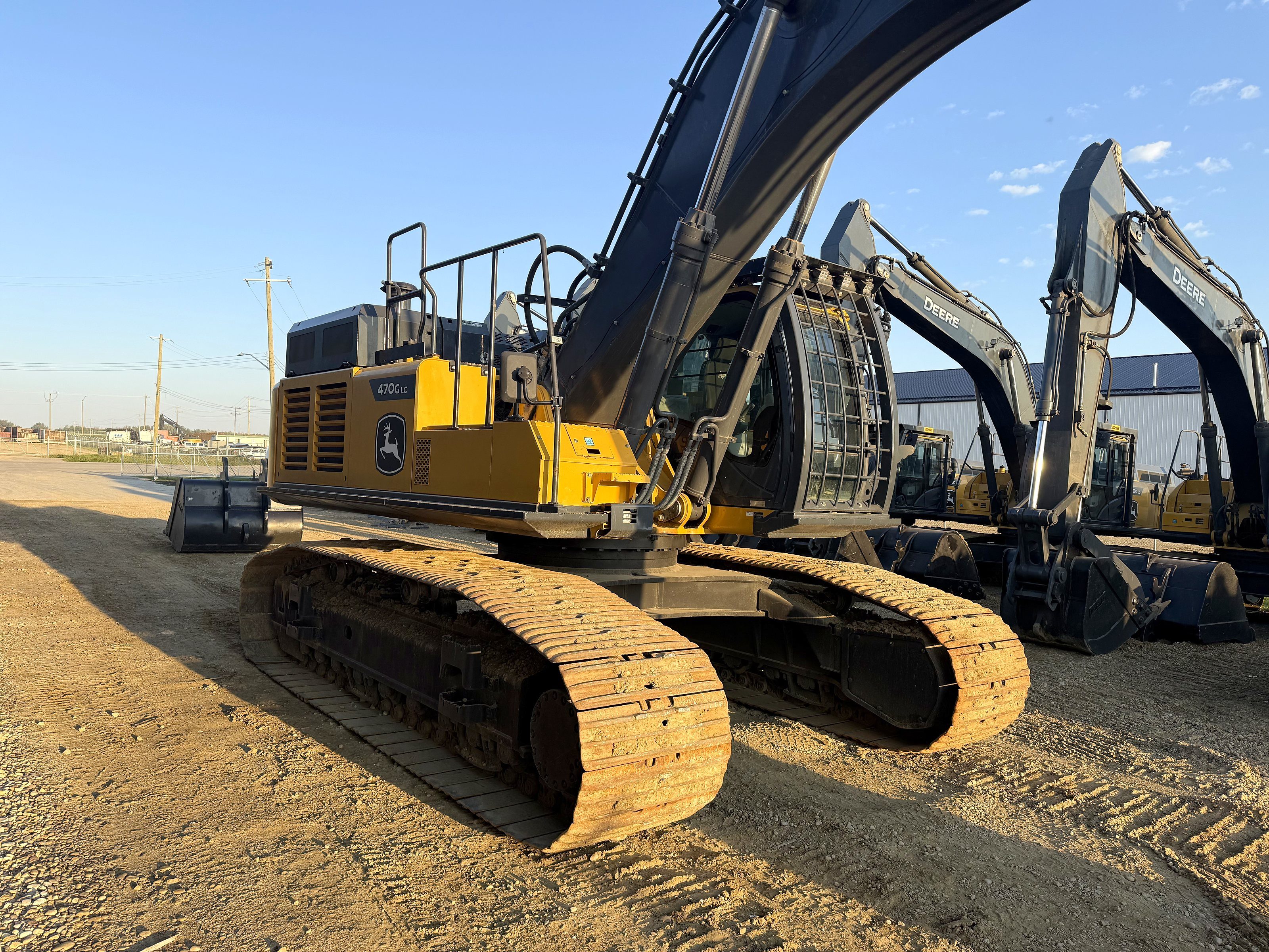 Large excavators lined up close in the yard in evening light
