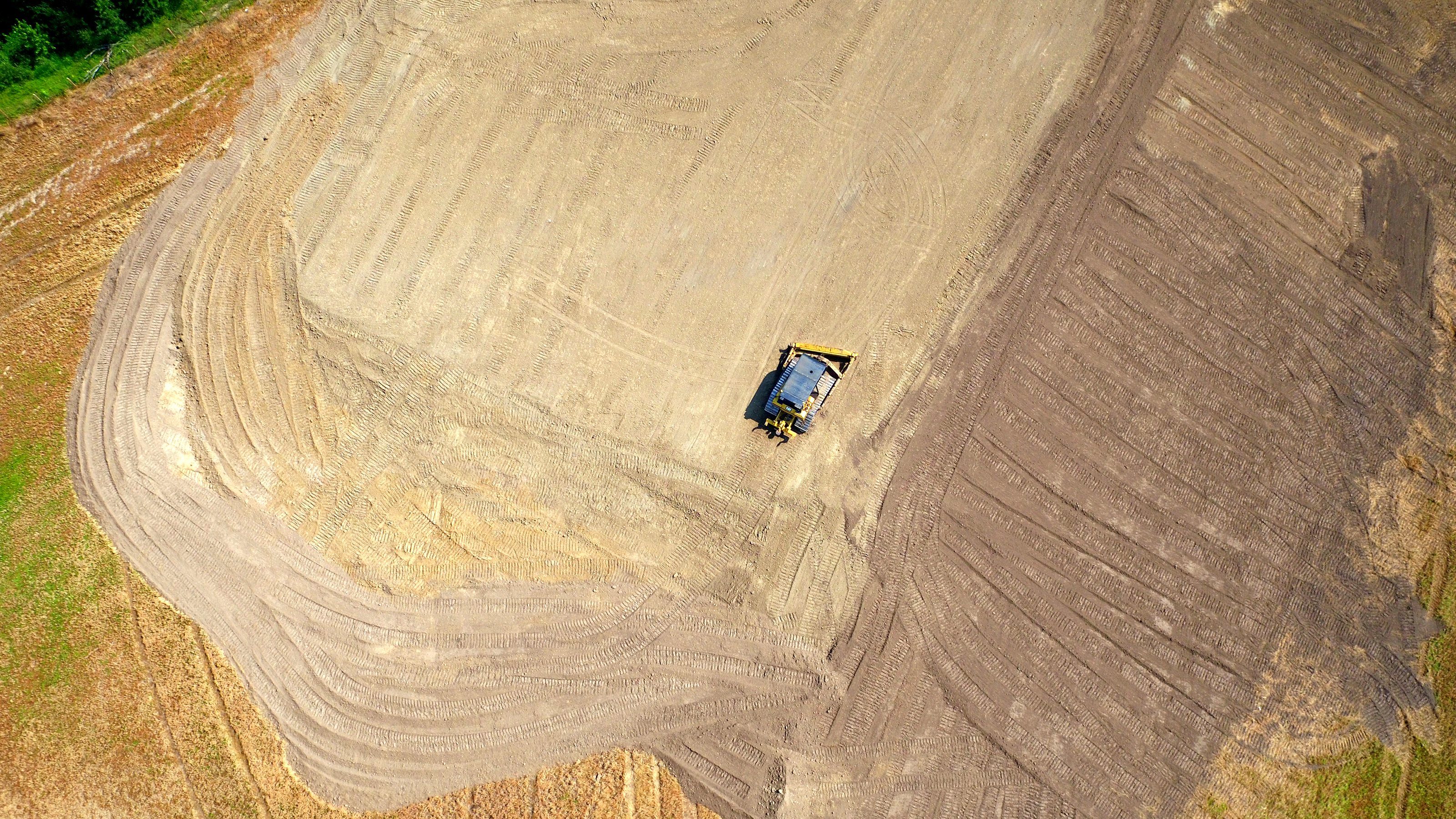 A machine grading a field seen from the air, the pass lines and the cut strip