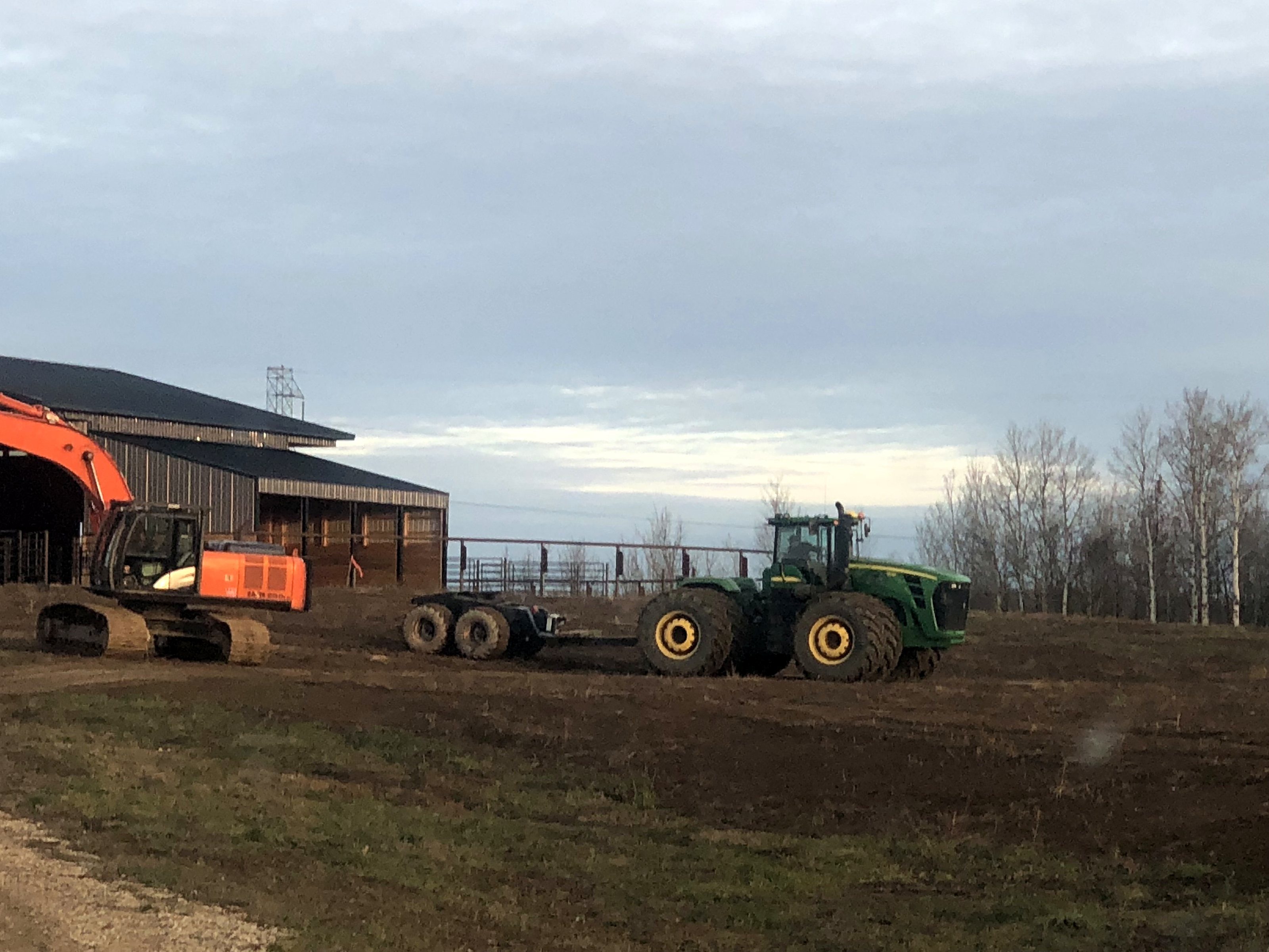 An excavator and a tractor standing in the yard at dusk