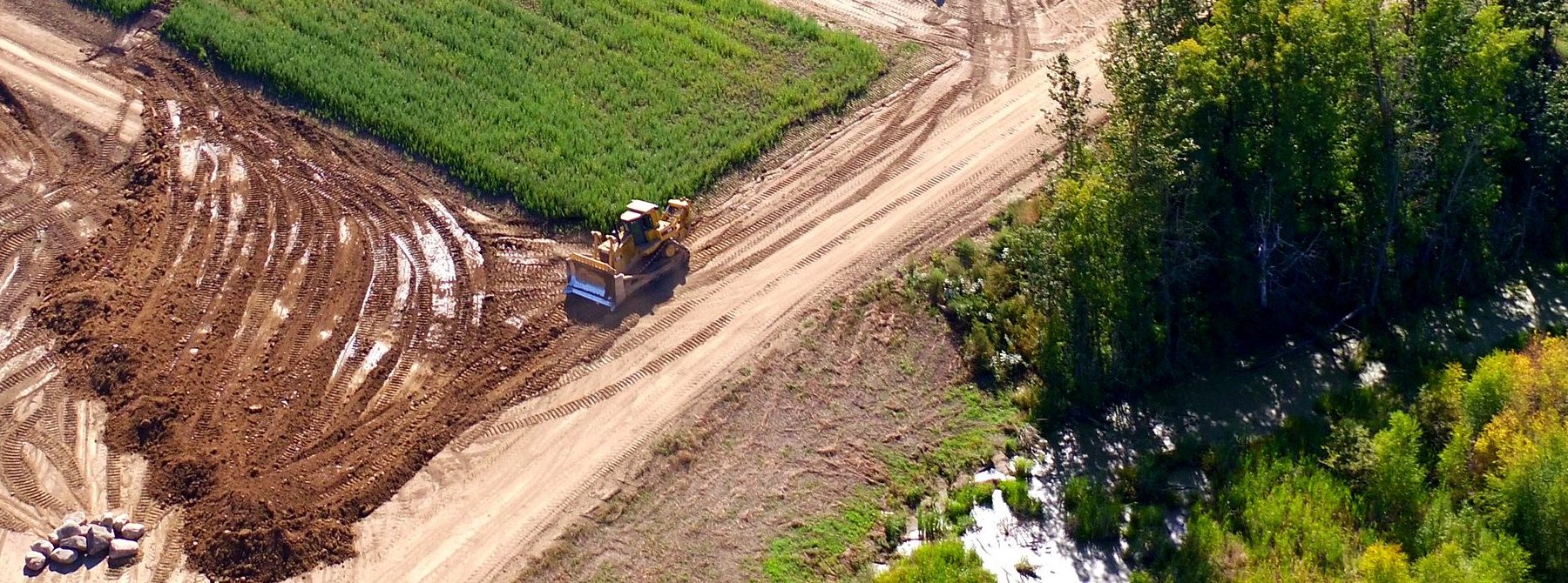 A cut face on the ranch earthworks seen from the air, the bank, the spoil and water standing at the toe