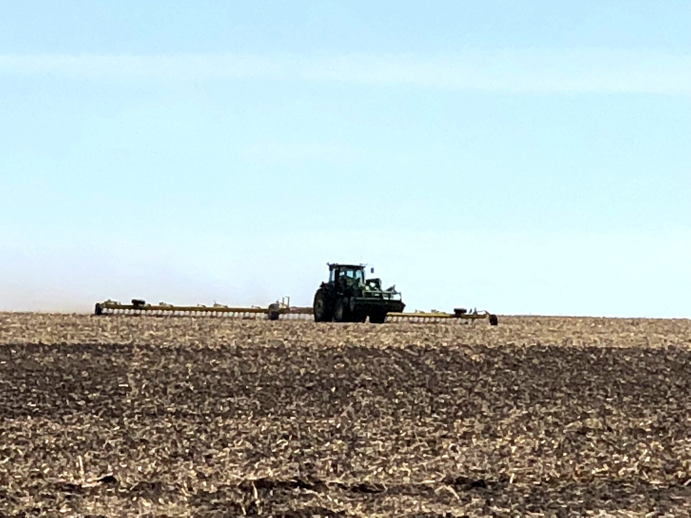 A tractor crossing a field at seeding time in spring