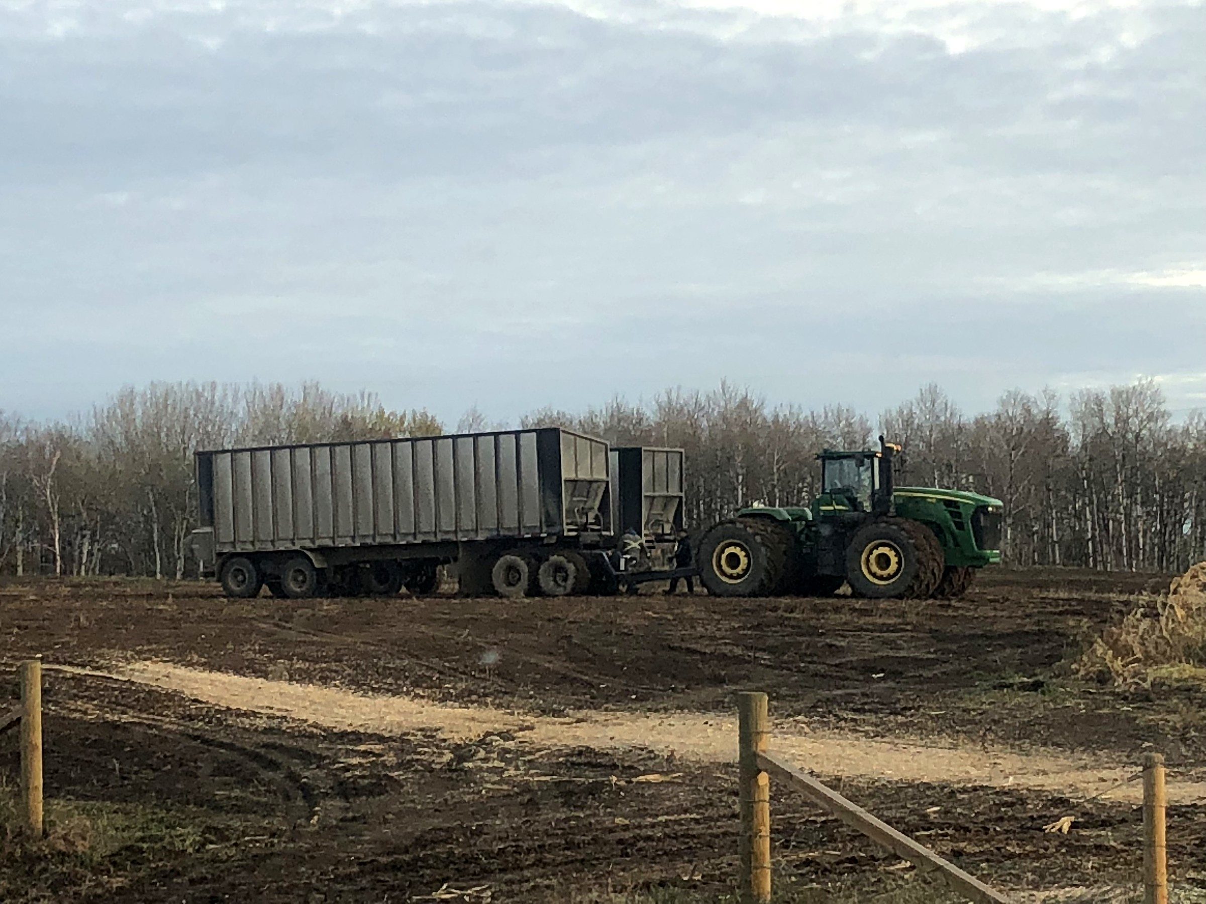 A tractor pulling a silage wagon along a field edge