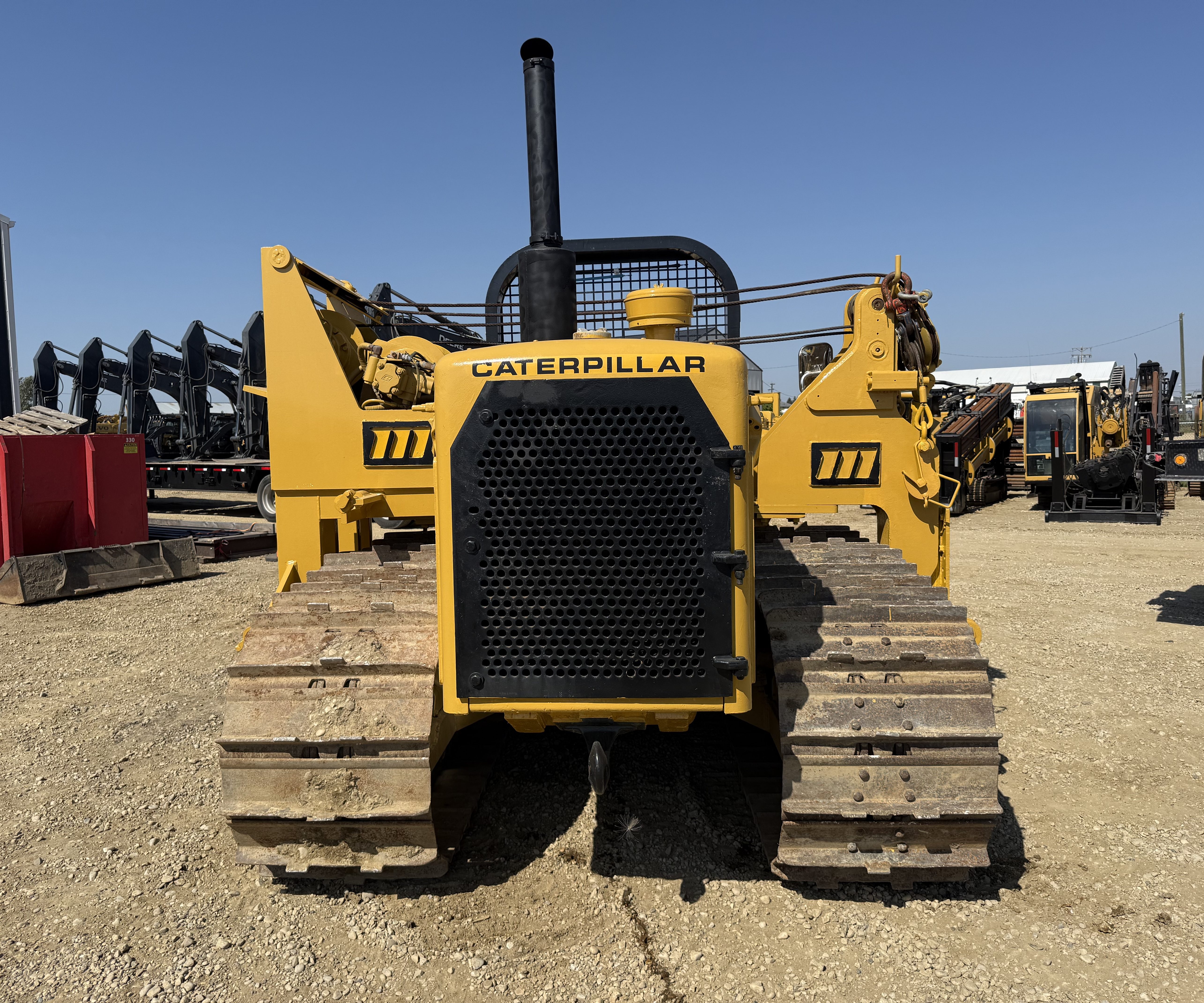 A pipelayer front-on with a row of excavators behind it