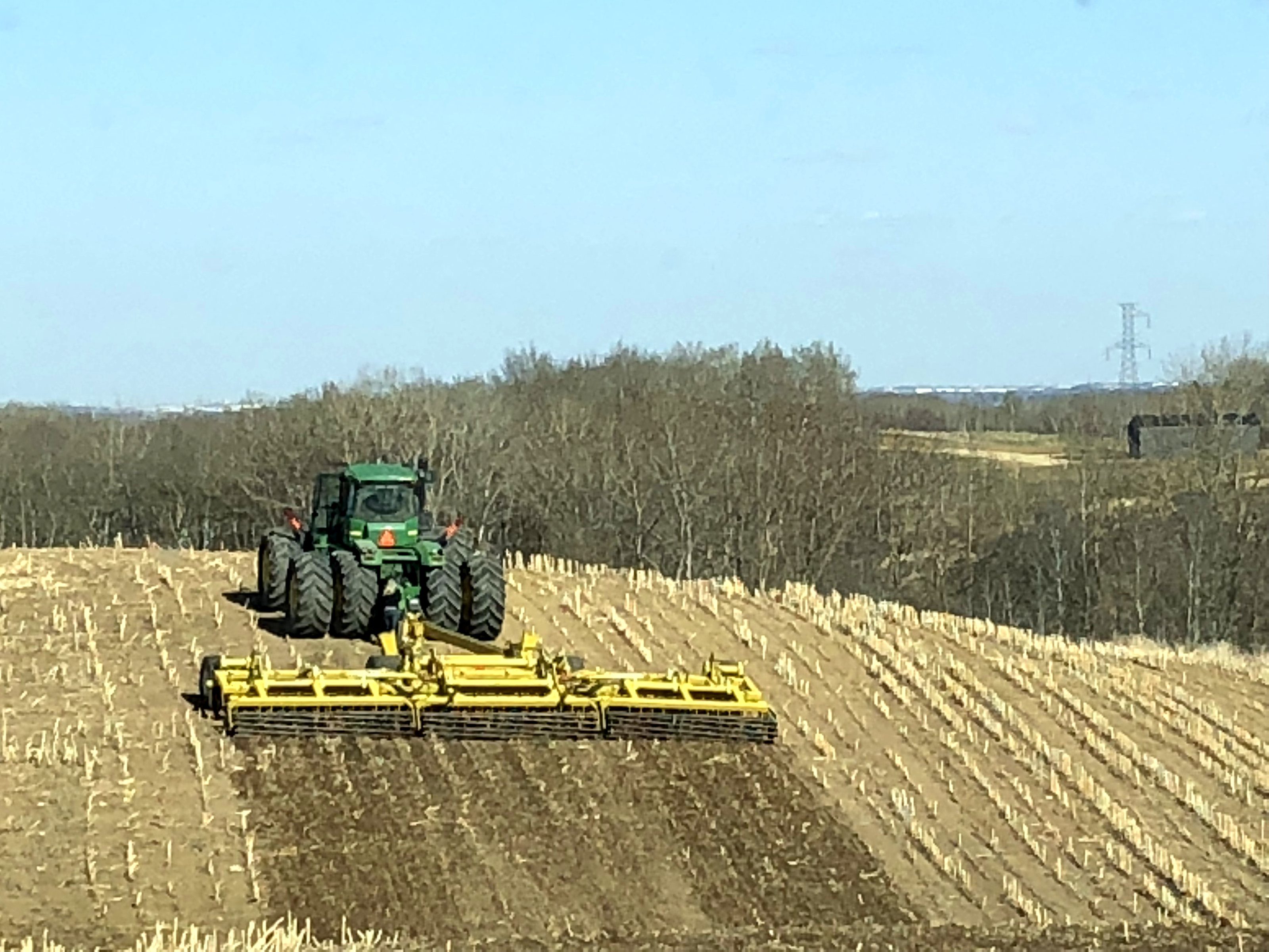 A tractor pulling a disc across a field in spring