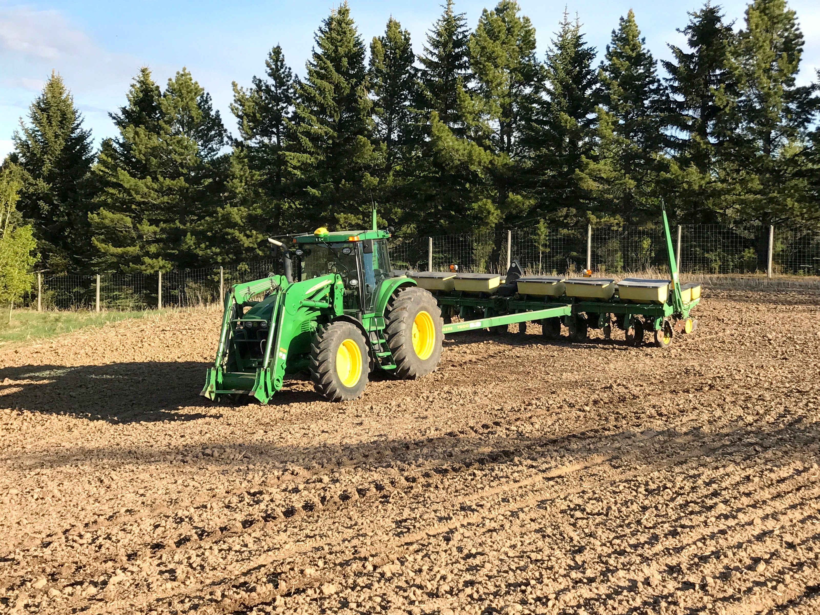 A tractor with a planter at the edge of a field in spring