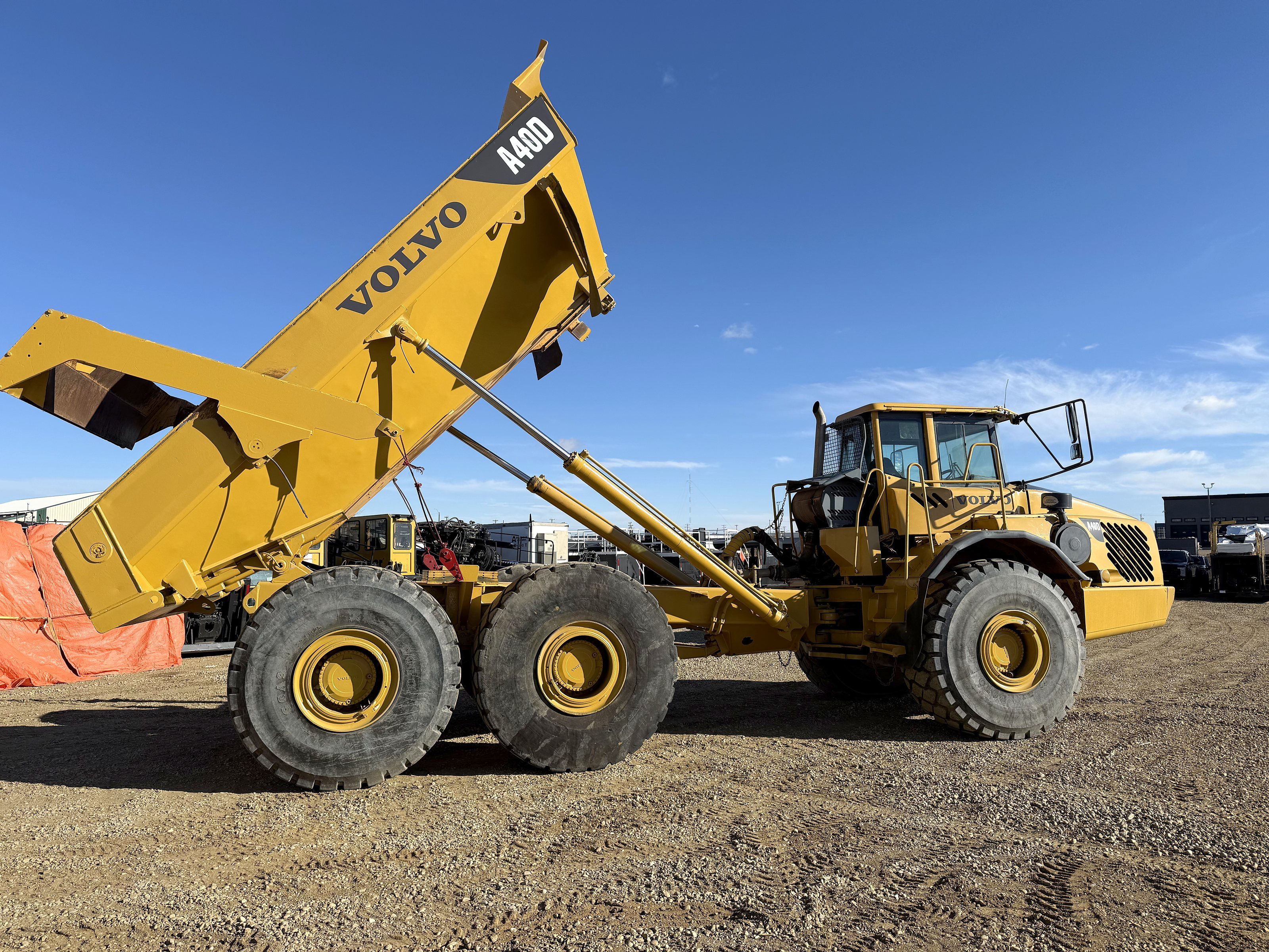 An articulated rock truck with its bed raised, in the yard